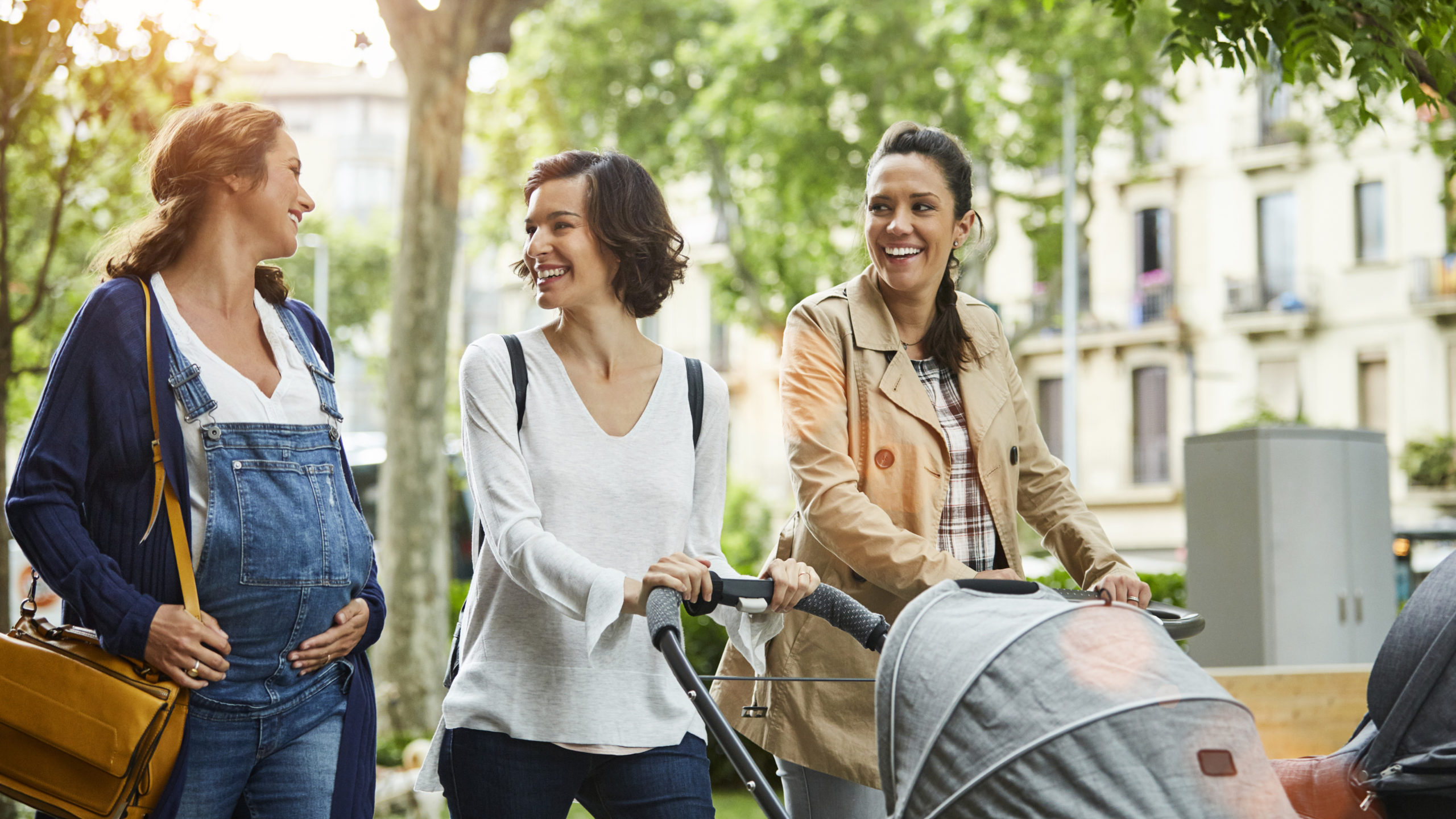 Happy pregnant woman with friends in park