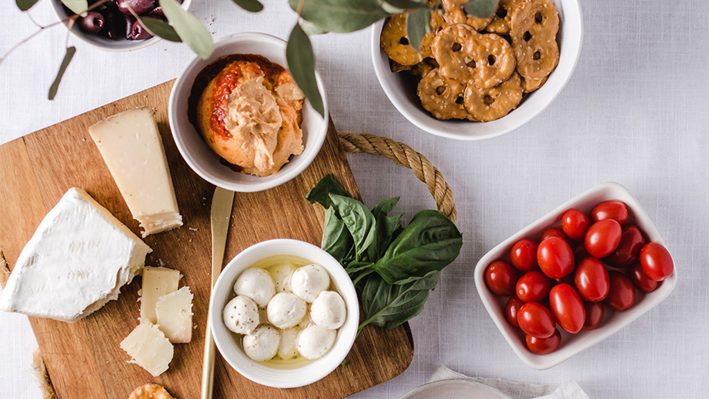 cheeseboard with cheese, dips, cherry tomatoes, and snack factory pretzel crisps