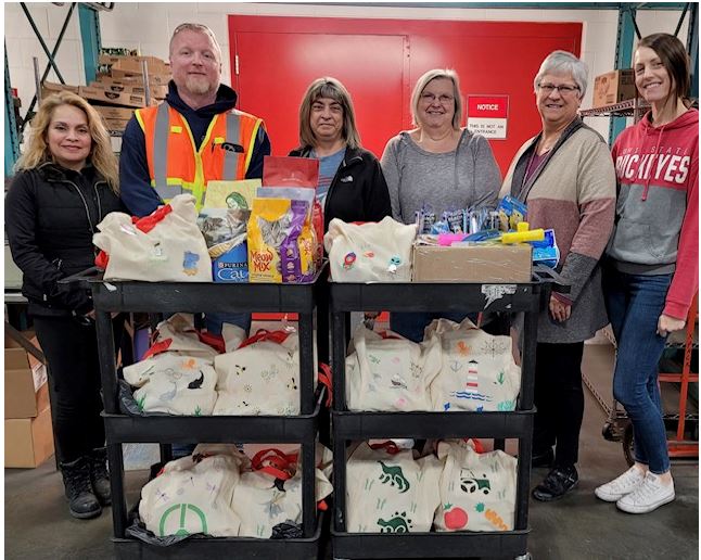 Napoleon employees pose with tote bags filled with donated items